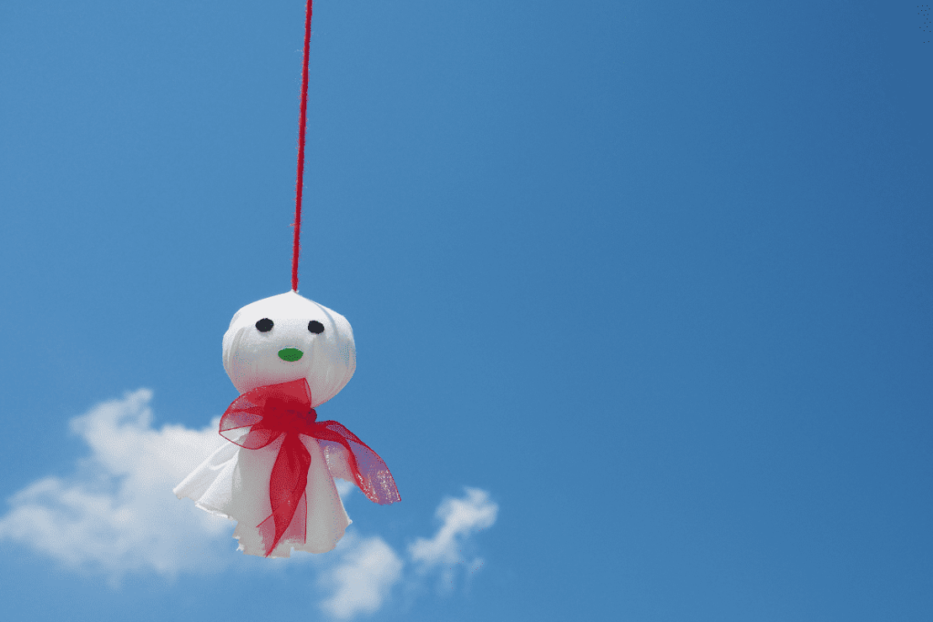 teru teru bozu pendurado por uma linha vermelha.